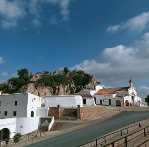 un groupe de bâtiments blancs avec une colline en arrière-plan dans l'établissement La casa de las piedras, 
