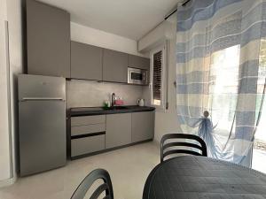 cocina con nevera, mesa y sillas en Appartamento Conchiglia-Immobili e Soluzioni Rent, en Lido Adriano