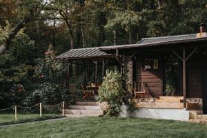 een blokhut met een veranda en een trap in een tuin bij refuges in Beauraing