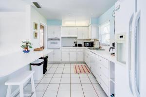 a white kitchen with white cabinets and blue walls at Cozy 60's home, city & canal located in Cape Coral