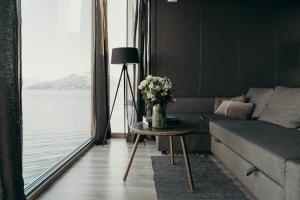 een woonkamer met een bank en een tafel met bloemen bij Aurora Fjord Cabins in Lyngseidet