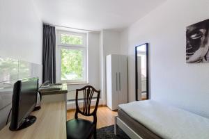 a bedroom with a bed and a desk and a chair at Voyage Pension in Leipzig