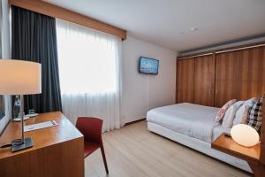 a hotel room with a bed and a desk and a television at Hotel Praia Marina by RIDAN Hotels in Praia da Vitória