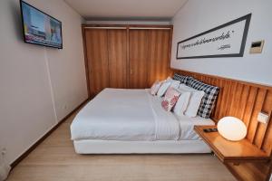 a bedroom with a large white bed and a table at Hotel Praia Marina by RIDAN Hotels in Praia da Vitória