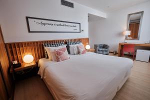 a bedroom with a large white bed with pillows at Hotel Praia Marina by RIDAN Hotels in Praia da Vitória