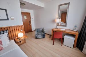 a hotel room with a bed and a desk with a mirror at Hotel Praia Marina by RIDAN Hotels in Praia da Vitória