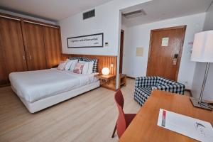 a hotel room with a bed and a desk and a chair at Hotel Praia Marina by RIDAN Hotels in Praia da Vitória
