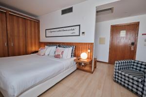a bedroom with a large white bed and a chair at Hotel Praia Marina by RIDAN Hotels in Praia da Vitória