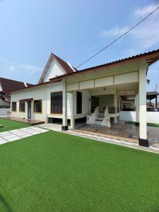 a house with a green lawn in front of it at Traditional Melaka Homestay with Private Pool in Kampong Bukit Katil