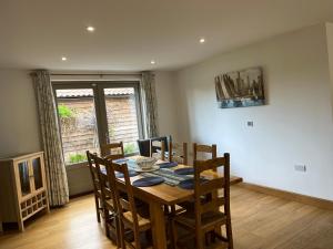 a dining room with a wooden table and chairs at Honeysuckle Barn, Martham in Great Yarmouth