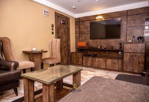 ein Wohnzimmer mit einem TV, einem Tisch und Stühlen in der Unterkunft Joker Hotel and Suites in Benin-Stadt