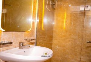 a bathroom with a sink and a shower with a mirror at Joker Hotel and Suites in Benin City