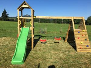 un parque infantil con tobogán y columpios en un campo en La Ferme de Madelonnet, en Saint-Jeures