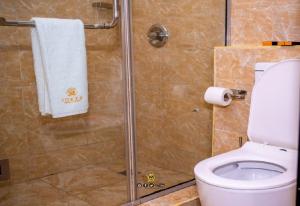 een badkamer met een douche, een toilet en een glazen douchecabine bij Joker Hotel and Suites in Benin City