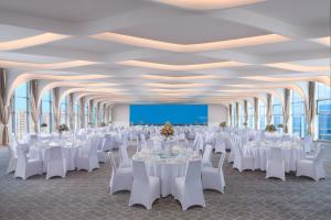 un salón de banquetes con mesas y sillas blancas y una pantalla en Le Meridien Shanghai Hongqiao,Minhang en Shanghái