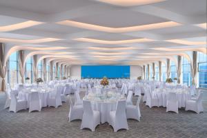 a banquet hall with white tables and chairs and a screen at Le Meridien Shanghai Hongqiao,Minhang in Shanghai