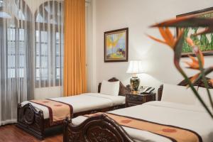 a room with two beds and a table with a lamp at Hanoi Little Town Hotel in Hanoi