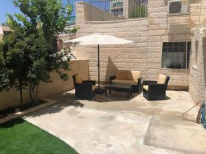 un patio con sombrilla, sofá y sillas en Tze'elam gardens super special NO Airbnb FEE's WOW, en Zanoaẖ