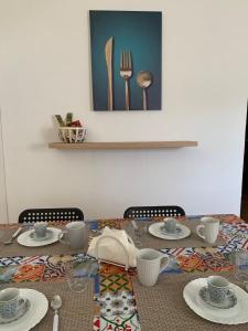 a table with plates and cups and utensils on it at Isola delle Femmine Apartment in Capaci in Capaci