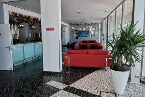 a living room with a red couch and a kitchen at Hotel Praia Marina by RIDAN Hotels in Praia da Vitória
