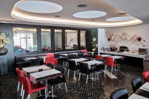 a dining room with tables and red chairs at Hotel Praia Marina by RIDAN Hotels in Praia da Vitória