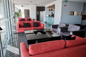 a living room with red chairs and a table at Hotel Praia Marina by RIDAN Hotels in Praia da Vitória