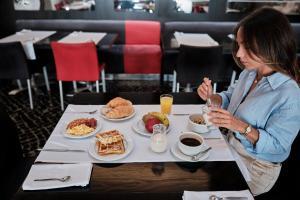 a woman sitting at a table with a plate of food at Hotel Praia Marina by RIDAN Hotels in Praia da Vitória
