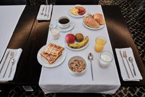 a table with breakfast foods and drinks on it at Hotel Praia Marina by RIDAN Hotels in Praia da Vitória