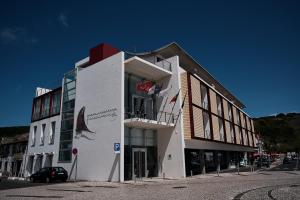 a white building with a car parked in front of it at Hotel Praia Marina by RIDAN Hotels in Praia da Vitória