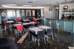 a restaurant with tables and chairs and a bar at Hotel Praia Marina by RIDAN Hotels in Praia da Vitória