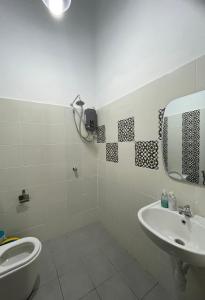 y baño con lavabo, aseo y espejo. en Traditional Melaka Homestay with Private Pool en Kampong Bukit Katil