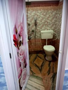 a bathroom with a toilet and flowers on the wall at SHALBITHI HOMESTAy in Bolpur