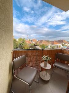 - un balcon avec 2 chaises et une table fleurie dans l'établissement Ellie Apartment, à Cluj-Napoca