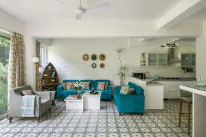 a living room with blue couches and a kitchen at El Rocio Estate in Assagao