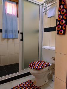 a bathroom with a shower and a toilet with a colorful seat at Airport Link Guest House in Entebbe