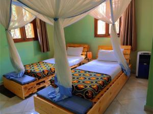 a bedroom with two beds and a canopy at Airport Link Guest House in Entebbe