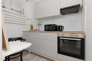 een keuken met witte kasten en een zwarte oven bij Spacious & Comfortable Studio Apartament Rajska with Balcony by Renters in Łódź
