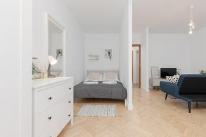 een witte slaapkamer met een bed en een blauwe stoel bij Spacious & Comfortable Studio Apartament Rajska with Balcony by Renters in Łódź