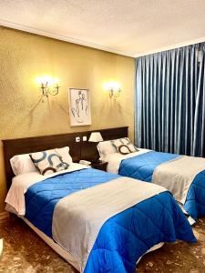 a hotel room with two beds with blue sheets at Hostal Sonsoles Madrid-Centro in Madrid