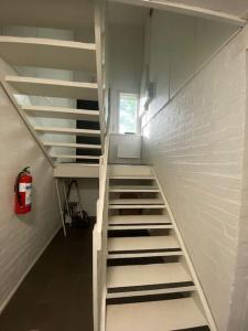 a white staircase in a room with a fire extinguisher at Kotimaailma: Hostel Kivikkotie (room 4) in Vantaa