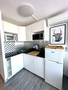 a kitchen with white cabinets and a picture of a bull at Studio vue port, parking privé, terrasse, clim in Le Grau-du-Roi