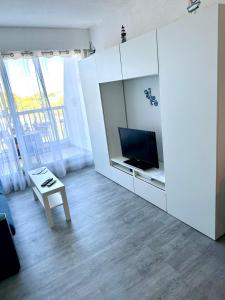 a white living room with a tv and a table at Studio vue port, parking privé, terrasse, clim in Le Grau-du-Roi