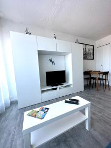 a living room with a white coffee table and a tv at Studio vue port, parking privé, terrasse, clim in Le Grau-du-Roi