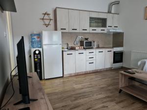 uma cozinha com armários brancos e um frigorífico branco em KARIBO apartman 3 em Sombor
