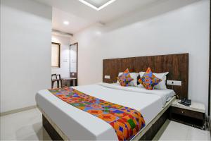 a bedroom with a large bed with a wooden headboard at FabHotel Krishna Inn in Bhiwandi