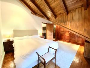 een slaapkamer met een wit bed en een stoel bij Apartamento Rustic Chic 28C in El Tarter