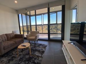 a living room with a couch and a tv at Serene Parkside Retreat 2Brs@ close 2 Olympic park in Sydney