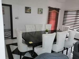 a dining room with a black table and white chairs at furnished 4 bd hse with pool in Accra