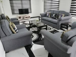 a living room with two couches and a tv at furnished 4 bd hse with pool in Accra