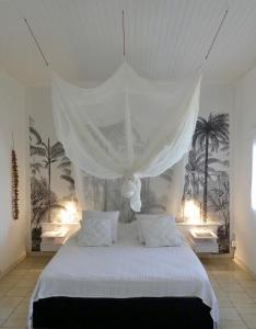 a bedroom with a white bed with a canopy at MANGOBELO entre océan et rivières in Capesterre-Belle-Eau